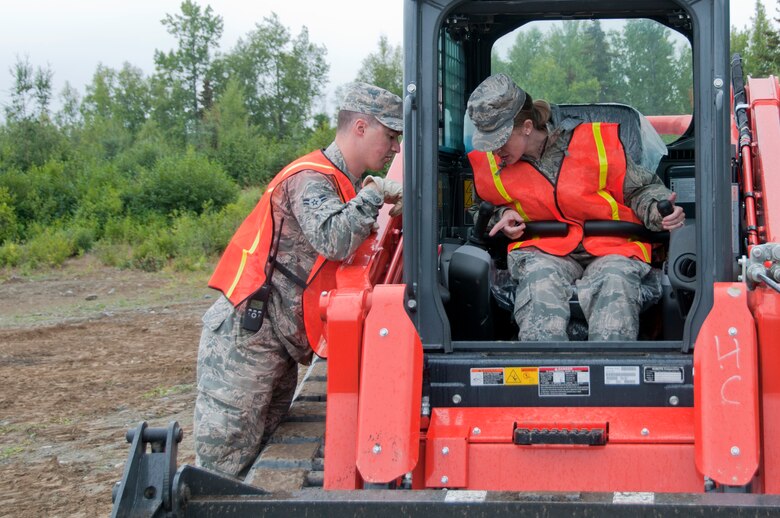 JOINT BASE ELMENDORF-RICHARDSON, Alaska -- Members of the 176th Civil Engineer Squadron practice operating a skid steer here Aug. 16, 2015, during the Polar Guard 15-1 exercise. Skills like this are a part of both their wartime mission and the state mission of urban search and rescue. (U.S. Air National Guard photo by Tech. Sgt N. Alicia Halla/ Released)