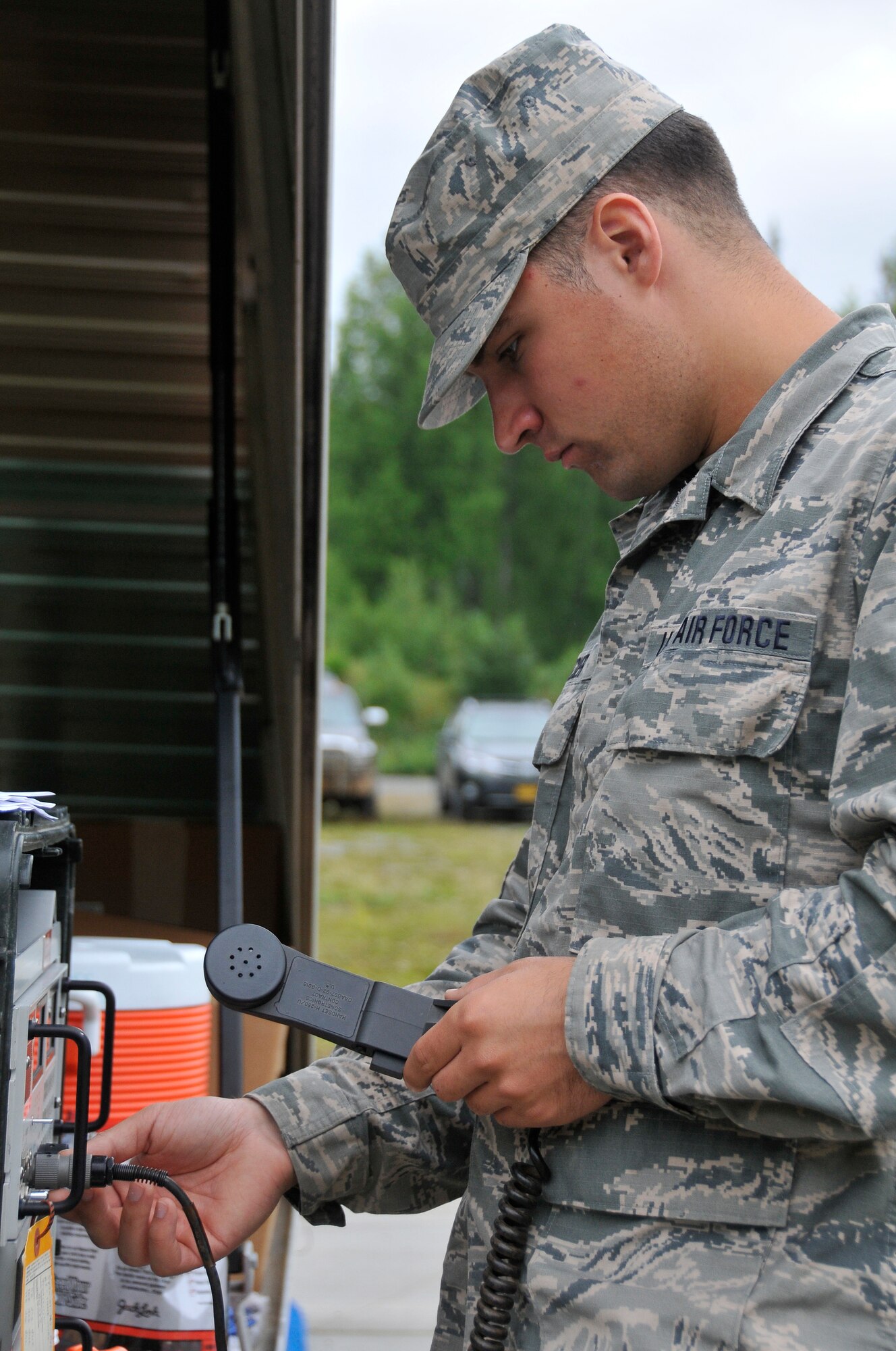 JOINT BASE ELMENDORF-RICHARDSON, Alaska -- Senior Amn. Justin Becker, a radio technician with the 176th Communications Flight, connects a hand mic to radio transmission equipment here Aug. 16, 2015, during the Polar Guard 15-1 exercise. Members of the 176th Mission Support Group from approximately 20 different job specialties train in their wartime mission skills during the four-day training. (U.S. Air National Guard photo by Tech. Sgt N. Alicia Halla/ Released)