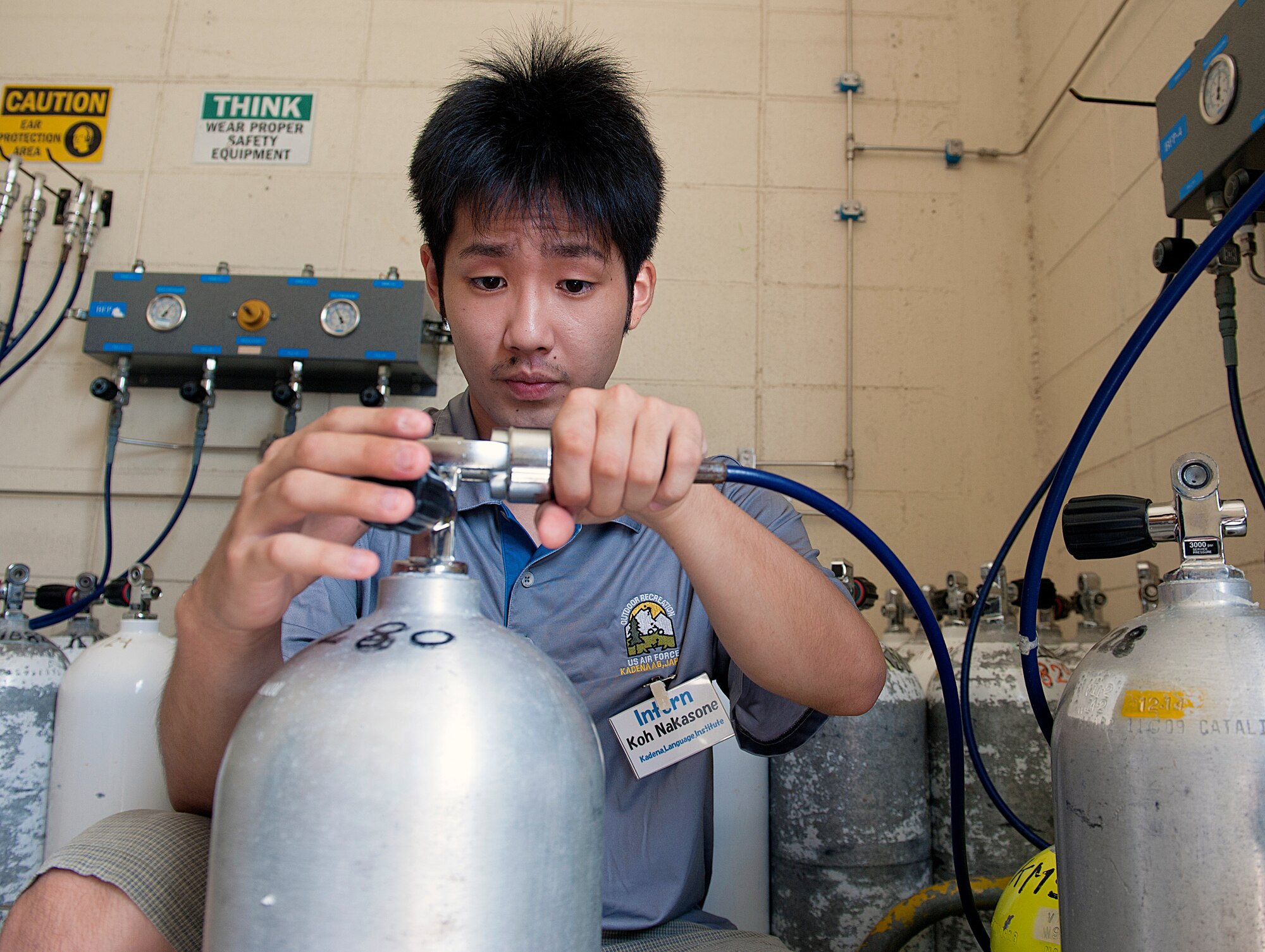 Koh Nakasone, Kadena Language Institute student intern, refills the oxygen of a scuba tank at the Kadena Marina on Okinawa, Japan, Aug. 21, 2015. The KLI Internship Program provides valuable experience to help improve the student's ability to communicate in English in a professional environment. (U.S. Air Force photo by Naoto Anazawa)
