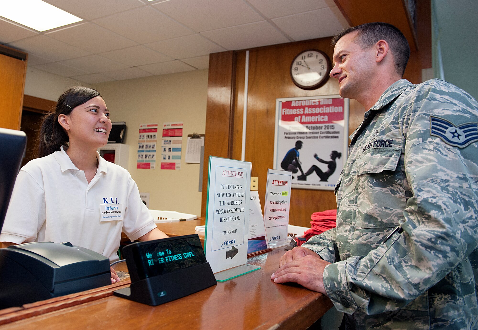 Noriko Nakagawa, Kadena Language Institute student intern, answers a question from U.S. Air Force Staff Sgt. Michael Canfield, 18th Medical Operations Squadron aerospace medical services technician at the Risner Fitness Center on Kadena Air Base, Japan, Aug. 21, 2015. The KLI program has been sponsored by Kadena for 16 years. (U.S. Air Force photo by Naoto Anazawa)

