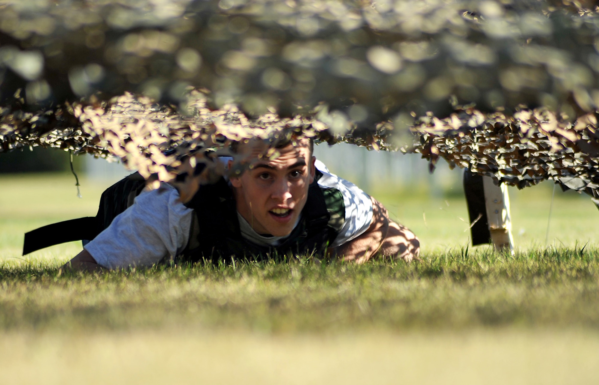 Airman 1st Class Levi Jackson, 319th Comptroller Squadron financial customer service technician, performs a low-crawl during the 2015 Summer Bash combat obstacle course on Grand Forks Air Force Base, North Dakota, Aug. 20, 2015. Airmen who participated in the combat obstacle course had to complete various tasks while wearing a weighted flak vest. (U.S. Air Force photo by Airman 1st Class Bonnie Grantham/released)