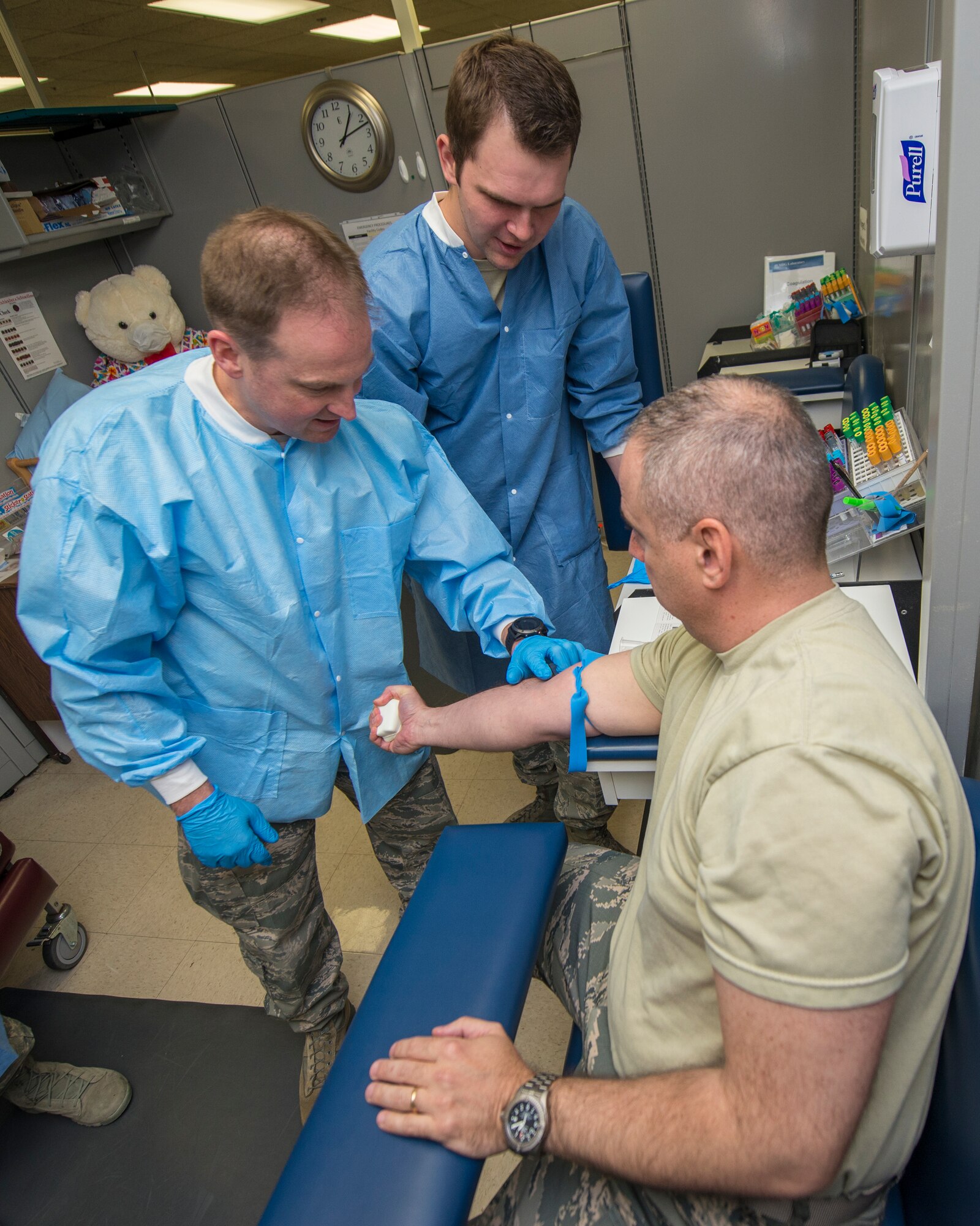 Col. Robert Kiebler, the 49th Wing commander, feels for a vein on Col. Paul Willingham, the 49th Medical Group commander, in order to draw blood under the direction of Senior Airman Mason Livermore, 49th Medical Group medical laboratory technician, at Holloman Air Force Base, N.M., Aug. 19. Every week the wing commander and the wing command chief make a face-to-face and hands-on visit to different parts of the base to get to know airmen and learn about their contribution to the mission. This week’s trip to the 49th Medical Group was focused on the medical laboratory where they learned about phlebotomy, urinalysis, hematology and chemistry. (U.S. Air Force photo by Senior Airman Aaron Montoya)