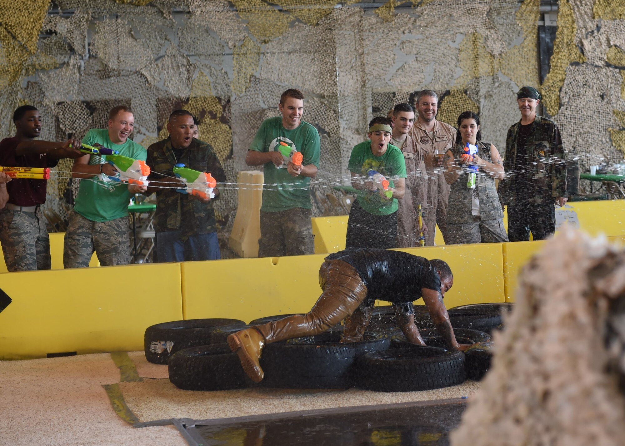 A Team Buckley member tries to run through the obstacle course while being sprayed by water guns during Combat Dining Out Aug. 21, 2015, at Hangar 909 on Buckley Air Force Base, Colo. Combat Dining Out is an annual event that included water fights, an obstacle course, a grog bowl, food, music, and is a spin on the more formal Combat Dining In, allowing spouses and guests to attend. (U.S. Air Force photo by Airman 1st Class Samantha Meadors/Released)