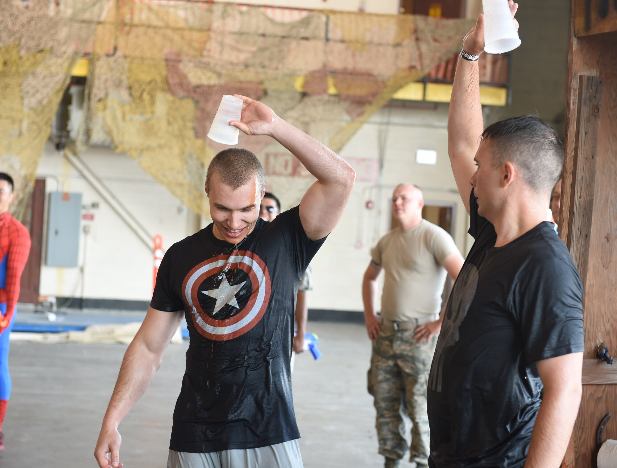 Two Combat Dining Out attendees put their empty cups over their heads after drinking from the grog bowl Aug. 21, 2015, at Hangar 909 on Buckley Air Force Base, Colo. Combat Dining Out is an annual event that included water fights, an obstacle course, a grog bowl, food, music, and is a spin on the more formal Combat Dining In, allowing spouses and guests to attend. (U.S. Air Force photo by Airman 1st Class Samantha Meadors/Released)