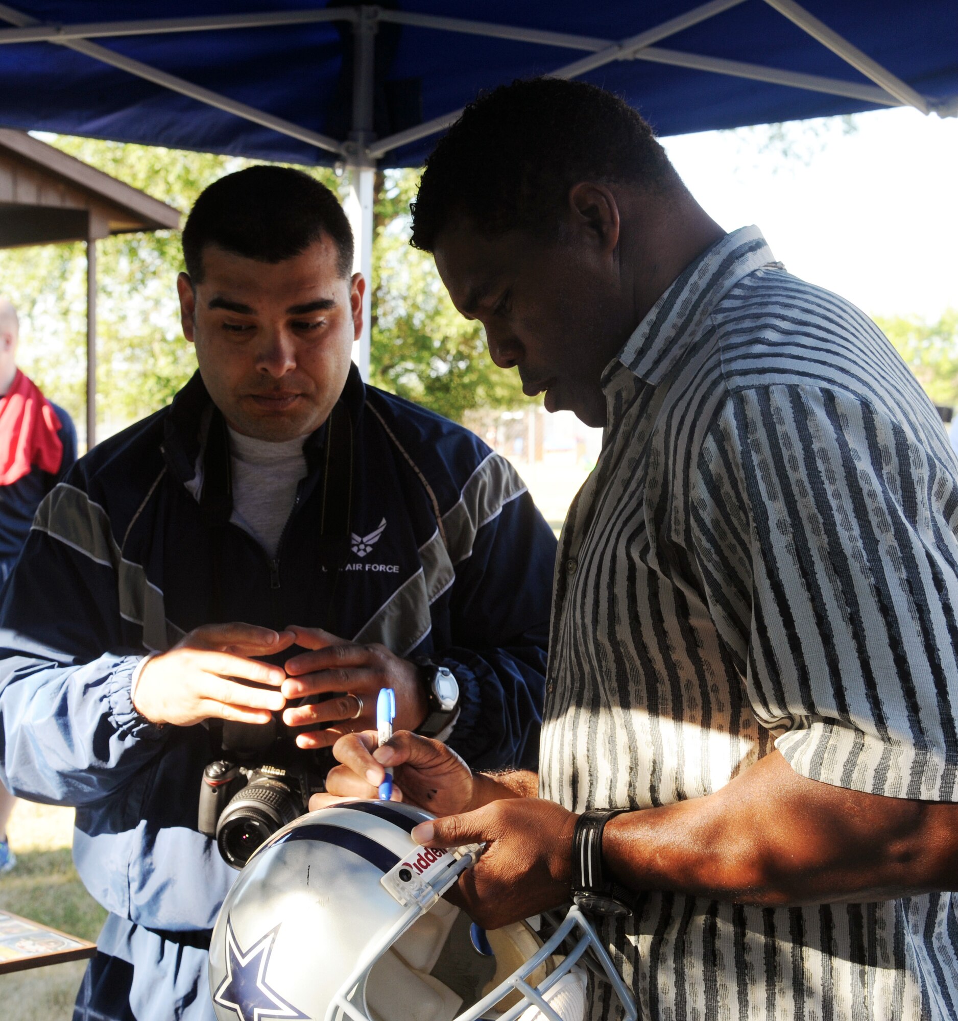 Herschel Walker signs football memorabilia for Staff Sgt. Luis Loza Gutierrez during a meet and greet session Aug. 20, 2015, at the Summer Bash sports grounds on Grand Forks Air Force Base, N.D. Walker spent the day with Airmen and was the guest speaker at the closing ceremony for the day's events. (U.S. Air Force photo/Senior Airman Desiree Economides)