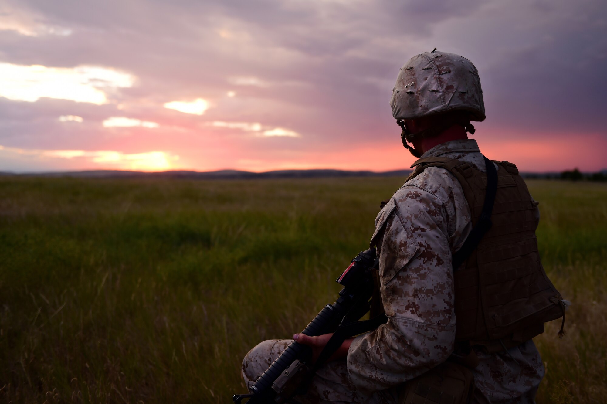 A Marine from Quebec Battery, 5th Battalion 14 Marines, looks out onto the countryside as he waits for the artillery guns to emplace at his position Aug. 14, 2015, in Guernsey, Wyoming. Before the guns emplace, an advanced party arrives at the scene where the Marines want to fire. These Marines set up where the guns will be laid, communications and a fire direction center for operations. (U.S. Air Force photo by Airman 1st Class Luke W. Nowakowski/Released)
