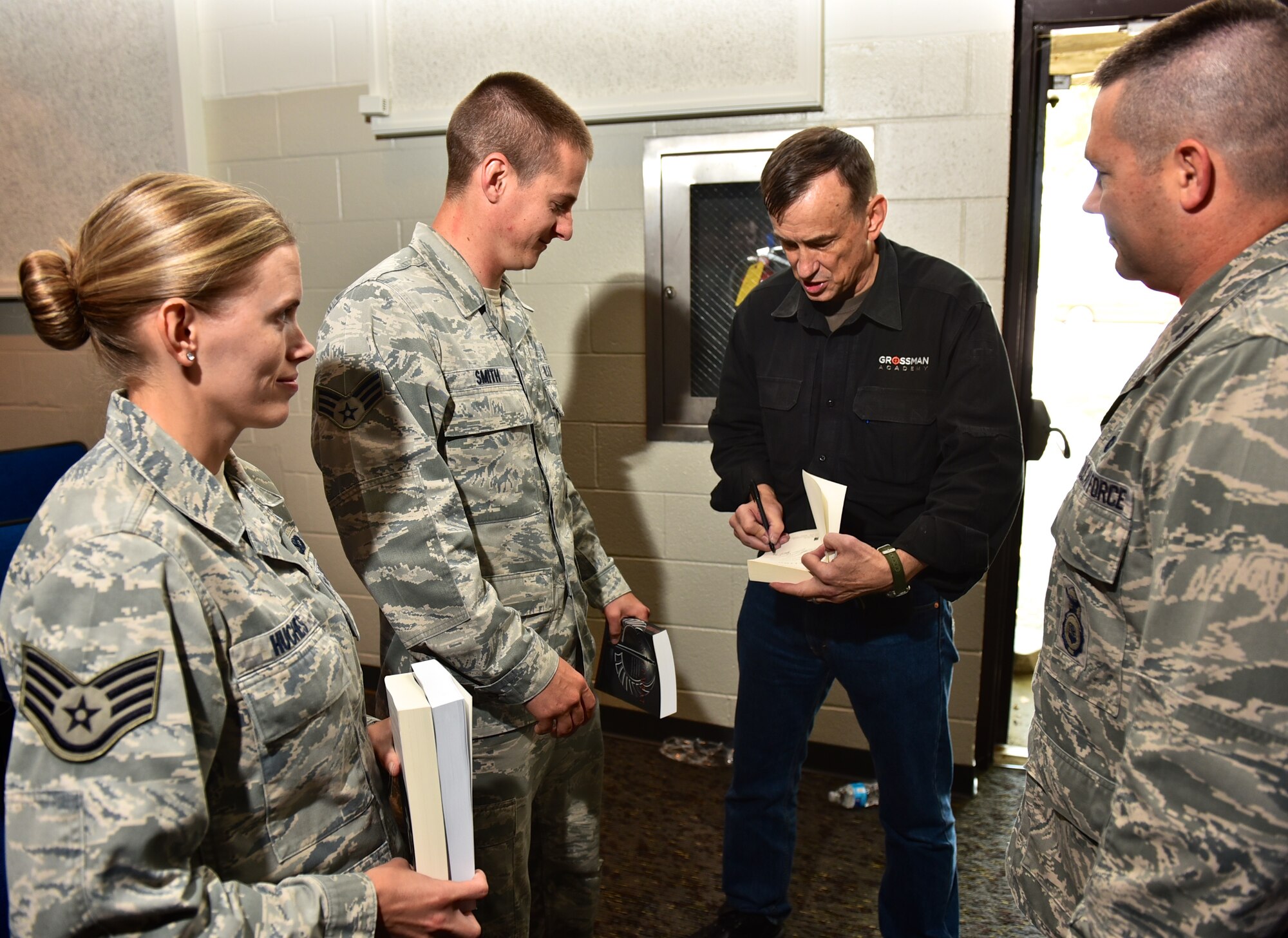 Senior Airman Kyle Smith, a fire team member with the 932nd Airlift Wing Security Forces Squadron has former Army Ranger Lt. Col. Dave Grossman sign a copy of one of Grossman's books during a lecture at the Scott Air Force Base Library auditorium, Aug. 21, 2015.  Grossman, a retired psychology professor from West Point, spoke to a crowd of primarily first responders and security forces personnel and hit on important topics to help combat Post traumatic Stress Disorder (PTSD), and the need to let the body rest.  Kyle said he enjoyed the book and that Grossman was an incredible speaker. (U.S. Air Force photo / Christopher Parr)