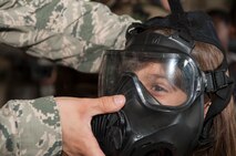 Staff Sgt. Wayne Baxter, 4th Civil Engineer Squadron unit deployment manager, fits a gas mask to a child during Operation Bug Out, Aug. 21, 2015, at Seymour Johnson Air Force Base, North Carolina. Children between the ages of five and 15 got the opportunity to go through a personnel deployment function line to experience what service members go through prior to deployment. (U.S. Air Force photo/Airman Shawna L. Keyes)