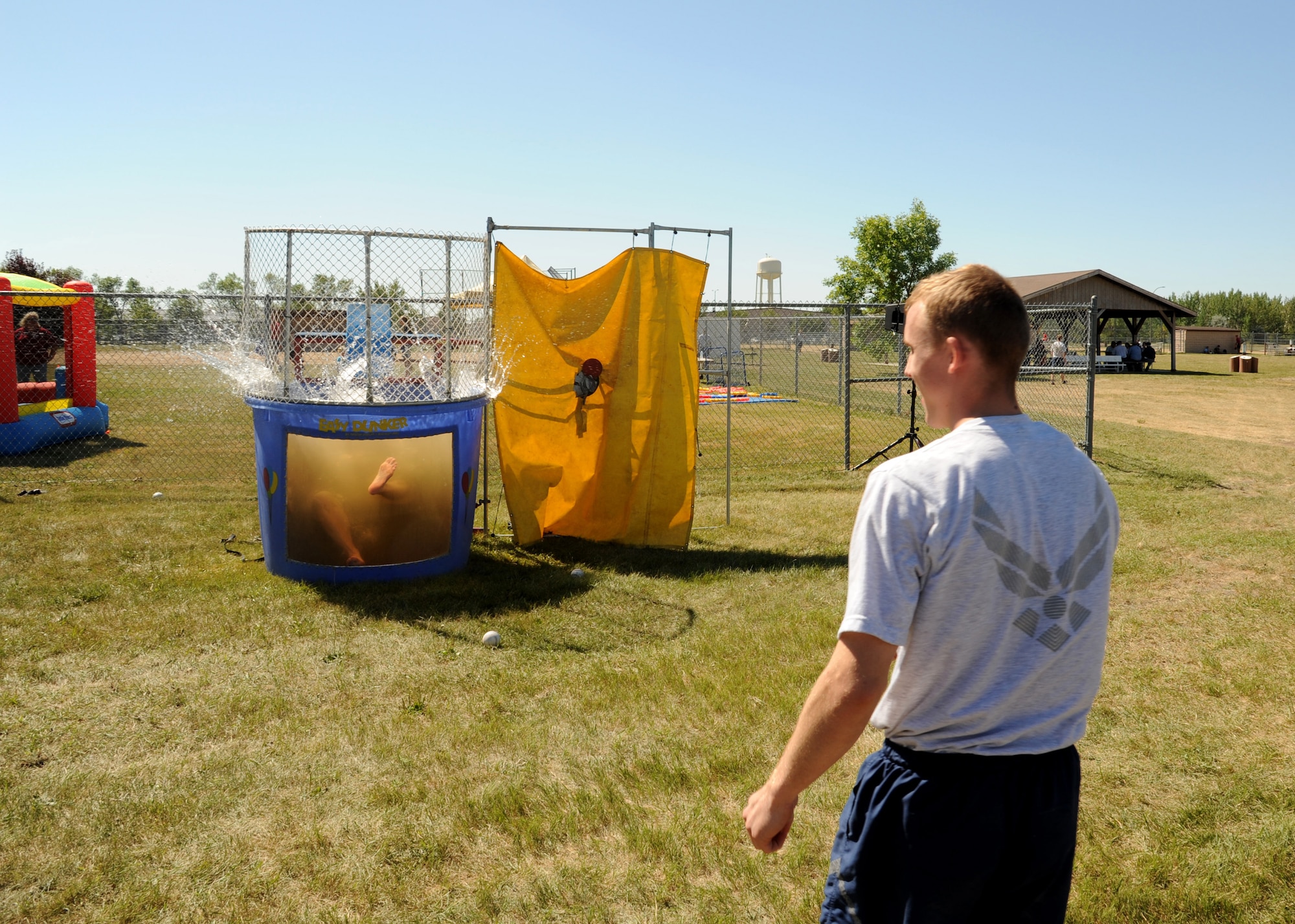 Airman 1st Class Levi Jackson, 319th Comptroller Squadron financial customer service technician, right, celebrates a successful throw at the dunk tank target August 20, 2105, on Grand Forks Air Force Base, North Dakota. The dunk tank at Summer Bash 2015 became the ?Duncan? Tank when Chief Master Sgt. David Duncan, 319th Air Base Wing command chief, volunteered to get dunked. The Airmen?s Activity Council provided the dunk tank for the event. (U.S. Air Force photo by Airman 1st Class Ryan Sparks/Released)