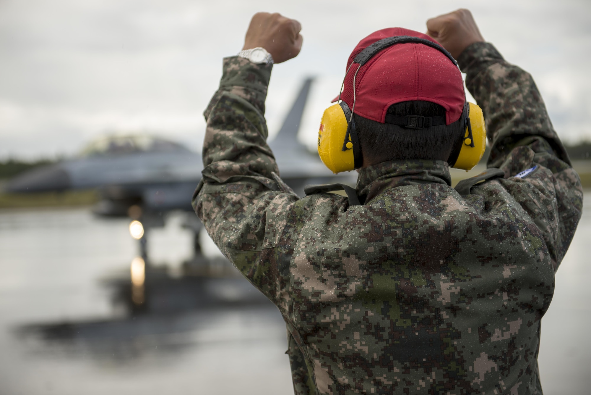 Republic of Korea Air Force (ROKAF) Warrant Officer Dongjun Lee, a ROKAF maintenance officer, signals to the pilots of a ROKAF F-16D Fighting Falcon after marshaling the aircraft through an unexpected rainstorm for a RED FLAG-Alaska (RF-A) 15-3 sortie, Aug. 11, 2015 at Eielson Air Force Base, Alaska. RF-A sorties are conducted for the full two-weeks, rain or shine, barring extreme inclement weather, providing participants with unparalleled training in the world’s largest instrumented air, ground and electronic combat training range in the world, the Joint Pacific Alaska Range Complex. (U.S. Air Force photo by 1st Lt. Elias Zani/Released)