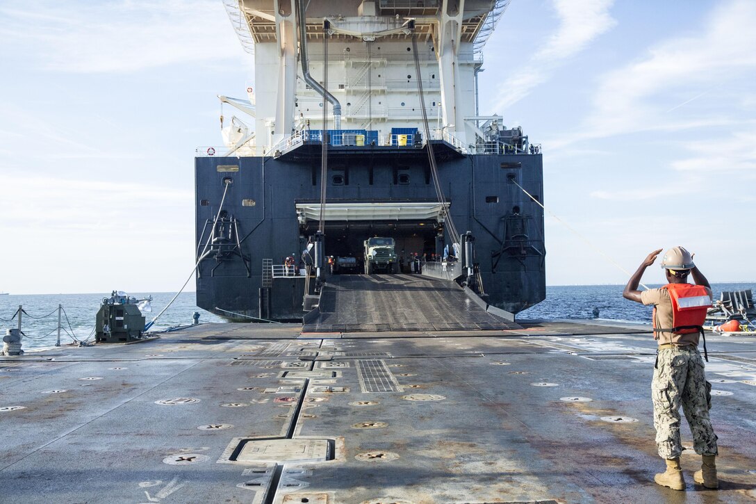 A sailor with Naval Beach Group 2 directs a seven-ton truck off of the USNS 1st Lt. Jack Lummus and onto a Roll-on/Roll-off Discharge Facility (RRDF), during an in-stream Marine Prepositioning Force Exercise, Aug. 19, 2015. Marines with Combat Logistics Regiment 25 and sailors with NBG-2 joined forces for the latest iteration of MPFEX, which saw service members offloading the Lummus using Lift-on/Lift-Off and Roll-on/Roll-off procedures off the coast of Marine Corps Support Facility Blount Island, Fla. (U.S. Marine Corps photo by Sgt. Shawn Valosin/Released)
