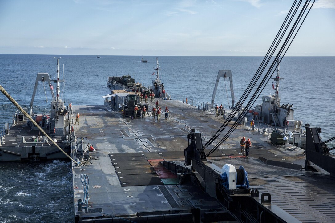 A Roll-on/Roll-off Discharge Facility and an Improved Navy Lighterage System are attached to the USNS 1st Lt. Jack Lummus with ropes and a ramp during a Marine Prepositioning Force Exercise, Aug. 19, 2015. The RRDF and INLS allowed Marines with Combat Logistics Regiment 25 and sailors with Naval Beach Group 2 to offload the Lummus using in-stream methods off the coat of Marine Corps Support Facility Blount Island, Fla. (U.S. Marine Corps photo by Sgt. Shawn Valosin/Released)