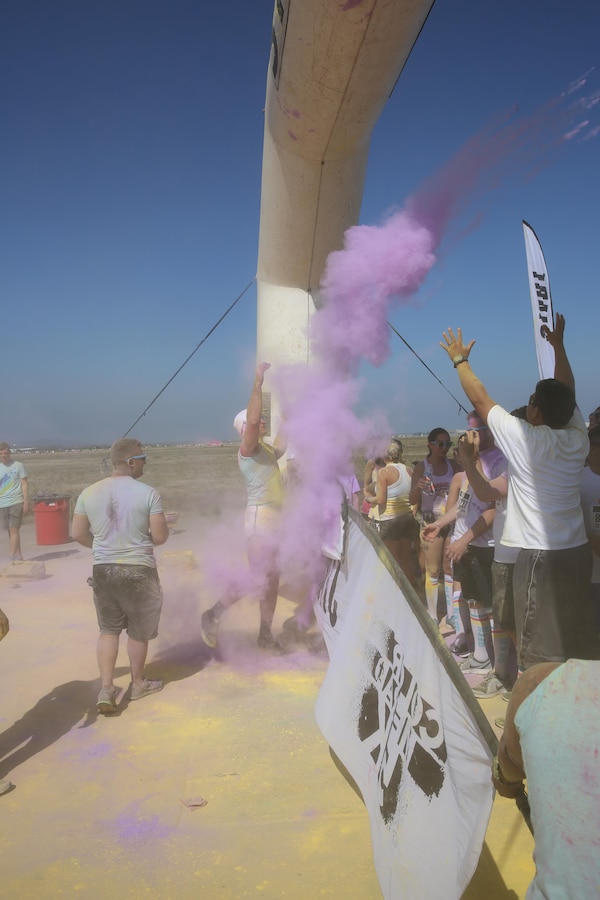 Lance Cpl. Col Hunsberger, a firefighter with Aircraft Rescue and Firefighting and an Edwardsburg, Michigan, native, tosses color powder at the participants during the Color Me Rad 5k aboard Marine Corps Air Station Miramar, California, Aug. 22. Marines and Sailors from units aboard MCAS Miramar volunteered for the event. (U.S. Marine photo by Lance Cpl. Kimberlyn Adams/Released)