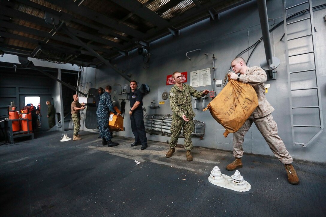 GULF OF ADEN (Aug. 22, 2015) U.S. Marine Sgt. Eric Gibbons, right, sorts mail with U.S. Sailors aboard the amphibious transport dock ship USS Anchorage (LPD 23) during a replenishment-at-sea. Gibbons is a radio operator with 1st Radio Battalion Detachment, Command Element, 15th Marine Expeditionary Unit. Elements of the 15th MEU are embarked aboard the Anchorage, which is part of the Essex Amphibious Ready Group, and are deployed in support of maritime security operations and theater security cooperation efforts in the U.S. 5th Fleet area of operations.  (U.S. Marine Corps photo by Sgt. Steve H. Lopez/Released)