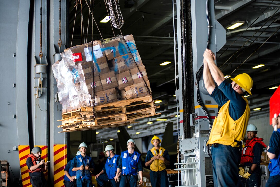 U.S. sailors receive cargo in the hangar bay of the USS John C. Stennis from USNS Henry J. Kaiser during a replenishment in the Pacific Ocean, Aug. 20, 2015. U.S. Navy photo by Petty Officer 3rd Class Jonathan Jiang
