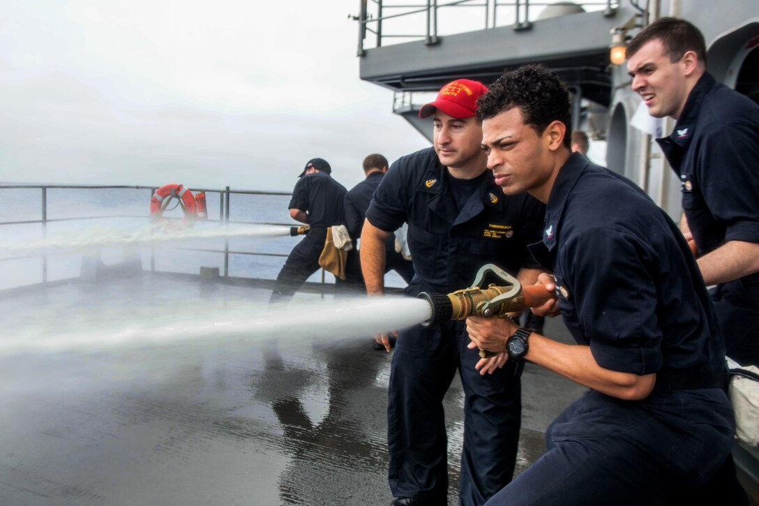 U.S. Navy Senior Chief Jason Thibodeaux, left, teaches U.S. Navy Petty Officer 3rd Class Wilber Pena how to handle a hose on the fantail of the USS John C. Stennis in the Pacific Ocean, Aug. 21, 2015. Thibodeaux is a hospital corpsman and Pena is an operations specialist. U.S. Navy photo by Petty Officer 3rd Class Jonathan Jiang
