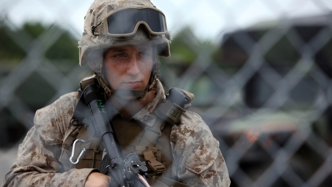 Lance Cpl. Jessie Stovicek stands post behind a chain-link fence during an airbase ground defense field operation at Marine Corps Auxiliary Landing Field Bogue, North Carolina, Aug. 19, 2015. Nearly 300 Marines with Marine Wing Support Squadron 271were involved in the field operation by providing security for ground operations during portrayed enemy attacks. Lark is an aircraft rescue and firefighting specialist with MWSS-271. Stovicek is a motor vehicle operator with MWSS-271.