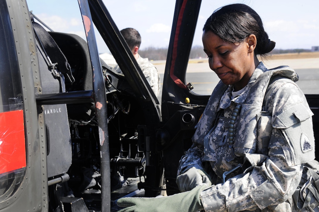 Army 1st Lt. Demetria N. Elosiebo puts on her gear before entering the cockpit of a UH-60 Black Hawk helicopter at Davison Army Airfield, Va., March 15, 2014. Elosiebo is a platoon leader assigned to Company D, Air Ambulance, 1st Battalion, 224th Aviation Regiment. 
Elosiebo is the first female African-American rotary wing pilot in the D.C. Army National Guard. Army National Guard photo by Staff Sgt. Mitch Miller