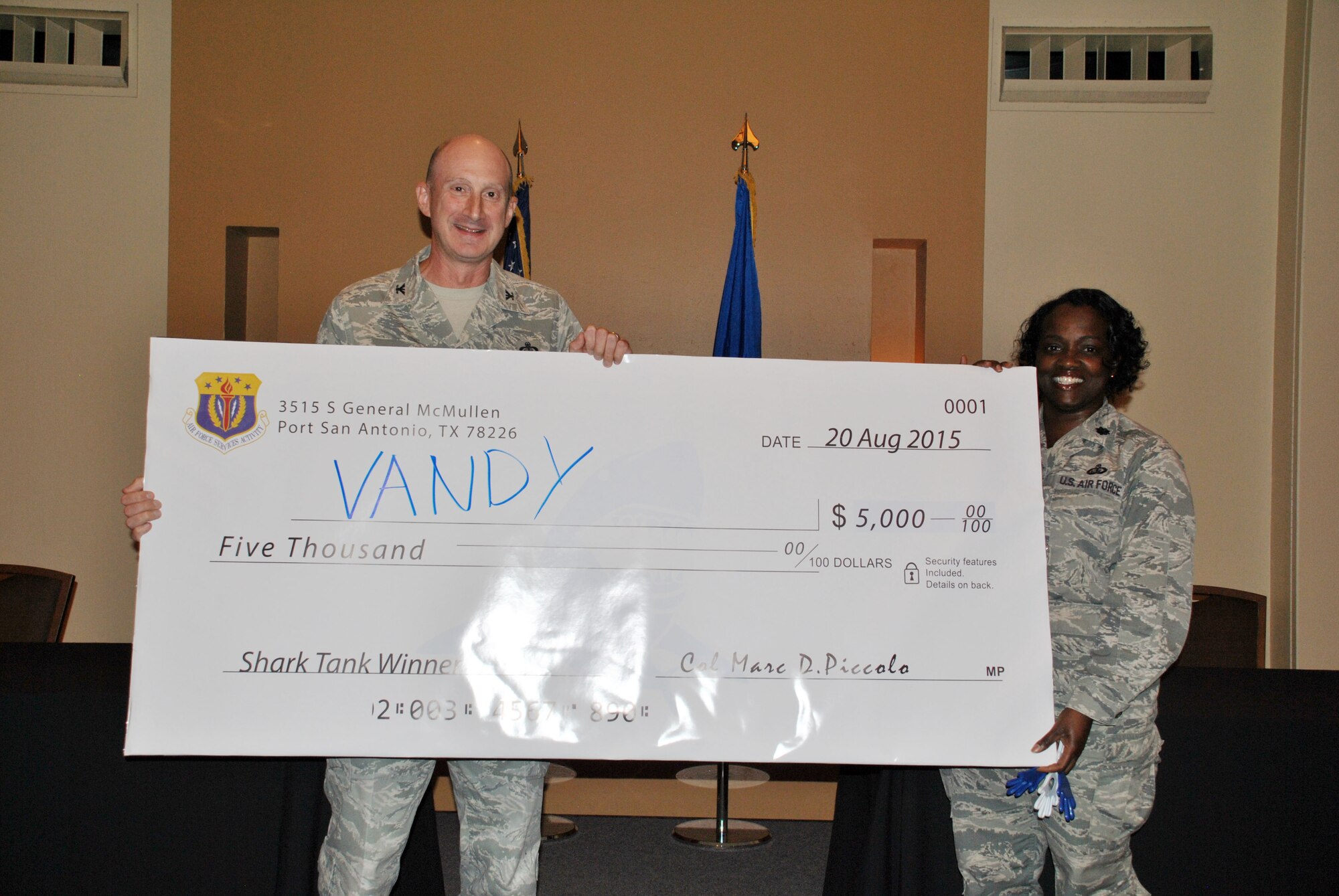 Air Force Services Activity commander Col. Marc Piccolo awards Lt. Col. Jileene Vivians, 30th Force Support Squadron commander from Vandenburg AFB, California, a $5,000 awards for her winning submission at a Shark Tank exercise at this year's FSS Training Event, Aug. 20, 2015. Her unit implemented a mobile text-based event notification system to base populace with a 75 percent increase in members reached. AFSVA hosted a FSS Training Event August 17-20, 2015, in San Antonio for FSS commanders and civilian leaders to learn about the present state of force support programs, future developments, innovation and network with each other. (U.S. Air Force photo/Master Sgt. Christian Michael/RELEASED)