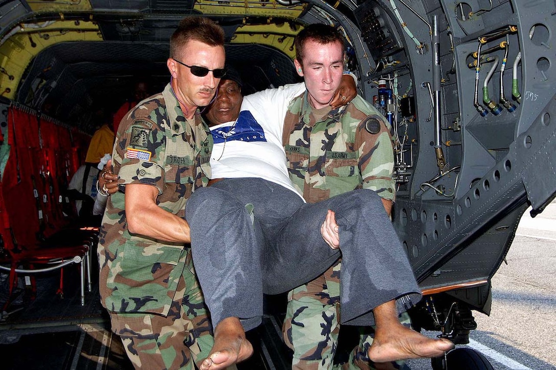 Army Spec. Trauth and Spec. Hanks carry a Hurricane Katrina victim from an Army CH-47 Chinook helicopter during relief efforts in New Orleans, Sept. 3, 2005. Trauth and Hanks are assigned to the Army National Guard.