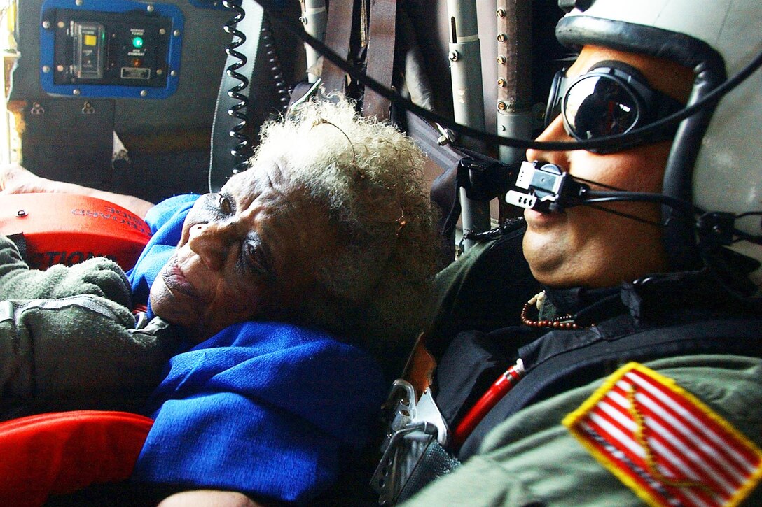 Navy search and rescue swimmer Petty Officer 1st Class Scott Chun comforts a victim of Hurricane Katrina pulled from a rooftop as they fly to safety aboard a U.S. Navy SH-60B Seahawk helicopter in New Orleans, Sept. 5, 2005. Chun is a search-and-rescue swimmer. U.S. Navy photo by Petty Officer 3rd Class Jay C. Pugh 
