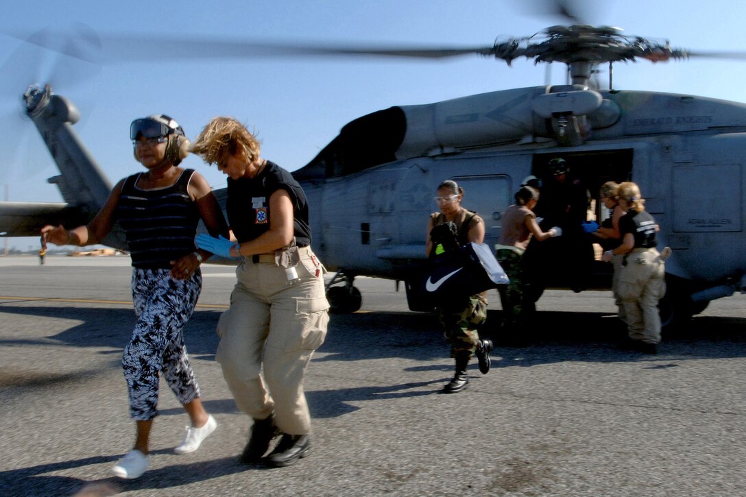 New Orleans residents walk from a U.S. Navy SH-60F Seahawk helicopter after they were evacuated from their homes and transported to New Orleans International Airport, Sept. 7, 2005, following Hurricane Katrina. The Seahawk is assigned to Helicopter Anti-Submarine Squadron 75, which was embarked on the aircraft carrier USS Harry S. Truman in the Gulf of Mexico. U.S. Navy photo by Petty Officer 3rd Class Kristopher Wilson