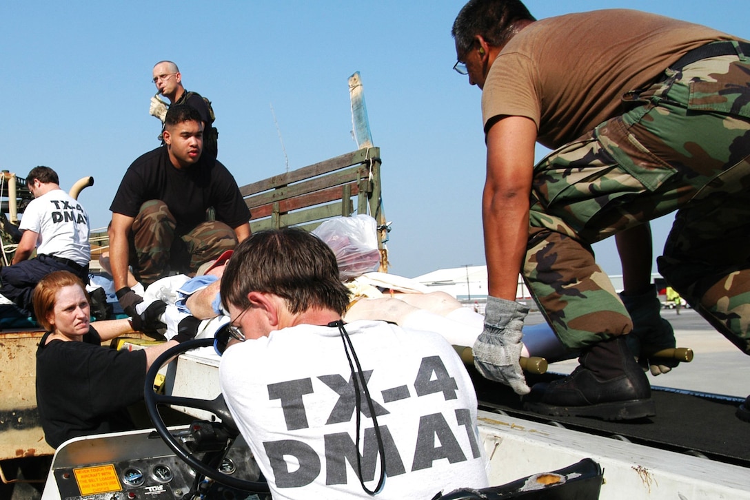 Members of the Louisiana National Guard and the Soldiers and members of a disaster medical assistance team from Texas ferry litter-borne evacuees from a truck for transport to a triage area inside the New Orleans Airport, Sept 2, 2005. Thousands of rescued residents stranded by Hurricane Katrina were evacuated to cities around the nation. Federal Emergecy Management Agency photo by Win Henderson