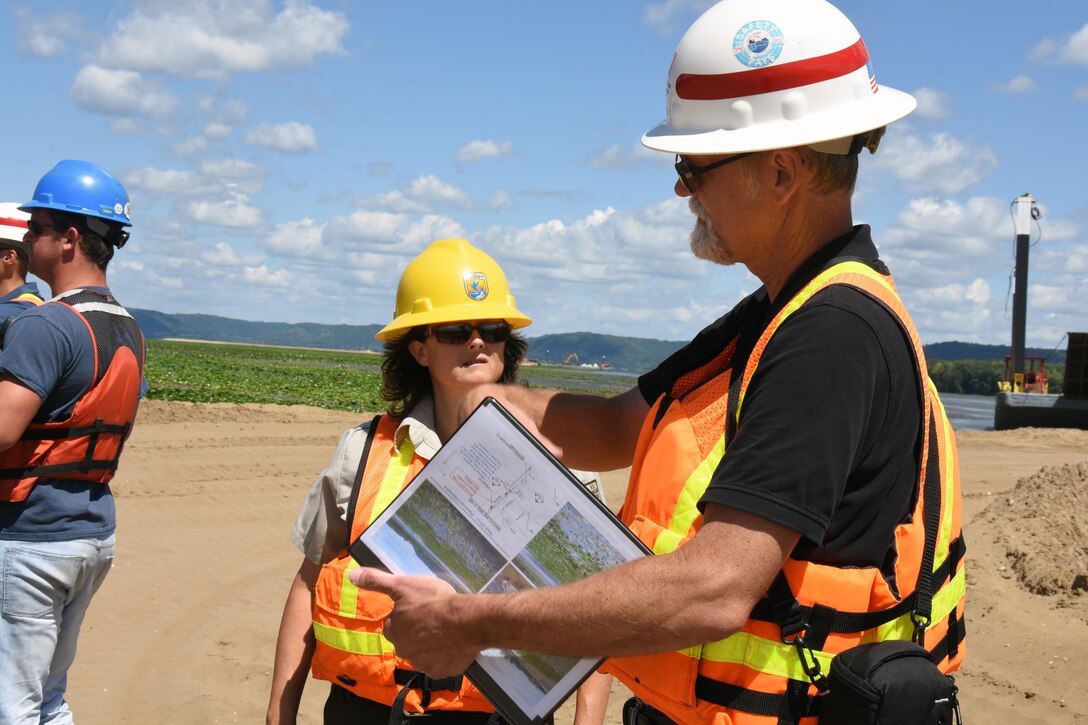 Resident engineer Scott Baker, center, talks with Sharonne Baylor of the U.S. Fish and Wildlife Service Aug. 11, 2015, during the weekly progress meeting for the Harper’s Slough project. The Harper’s Slough Habitat Rehabilitation and Enhancement Project, located within the Upper Mississippi River National Wildlife and Fish Refuge, was planned and designed under the authority of the Upper Mississippi River Restoration Program. It will protect five existing islands and construct an additional seven islands using material from the backwater and main channel. The program emphasizes habitat rehabilitation and enhancement projects and long-term resource monitoring. Project component includes dredging backwater areas and channels, constructing dikes, creating and stabilizing islands and controlling side channel flows and water levels. Once the project is completed, the project will be turned over to the U.S. Fish and Wildlife Service, who manages the refuge.