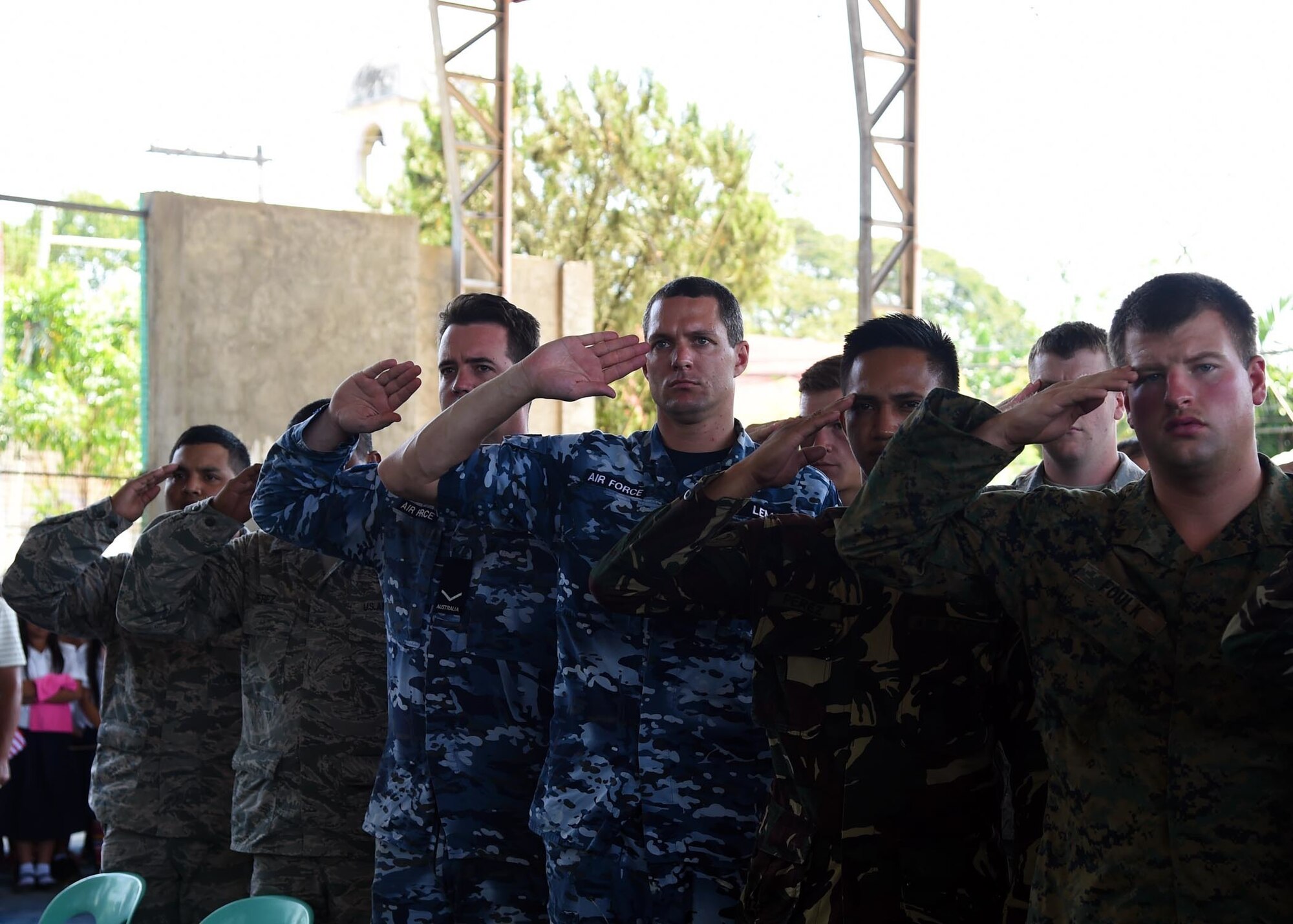 Members from the U.S. military, the Philippine Air Force and the Royal Australian Air Force salute as the Philippine national anthem is played during the Pacific Angel Philippine closing ceremony in Bohol Province, Philippines, Aug. 24, 2015. Over the course of six days, 5,101 patients received health care and six different schools were refurbished providing rehabilitated learning space to about 5,000 students. Pacific Angel is a multilateral humanitarian assistance civil military operation, which improves military-to-military partnerships in the Pacific while also providing medical health outreach, civic engineering projects and subject matter exchanges among partner forces.(U.S. Air Force photo by Tech. Sgt. Aaron Oelrich/Released)