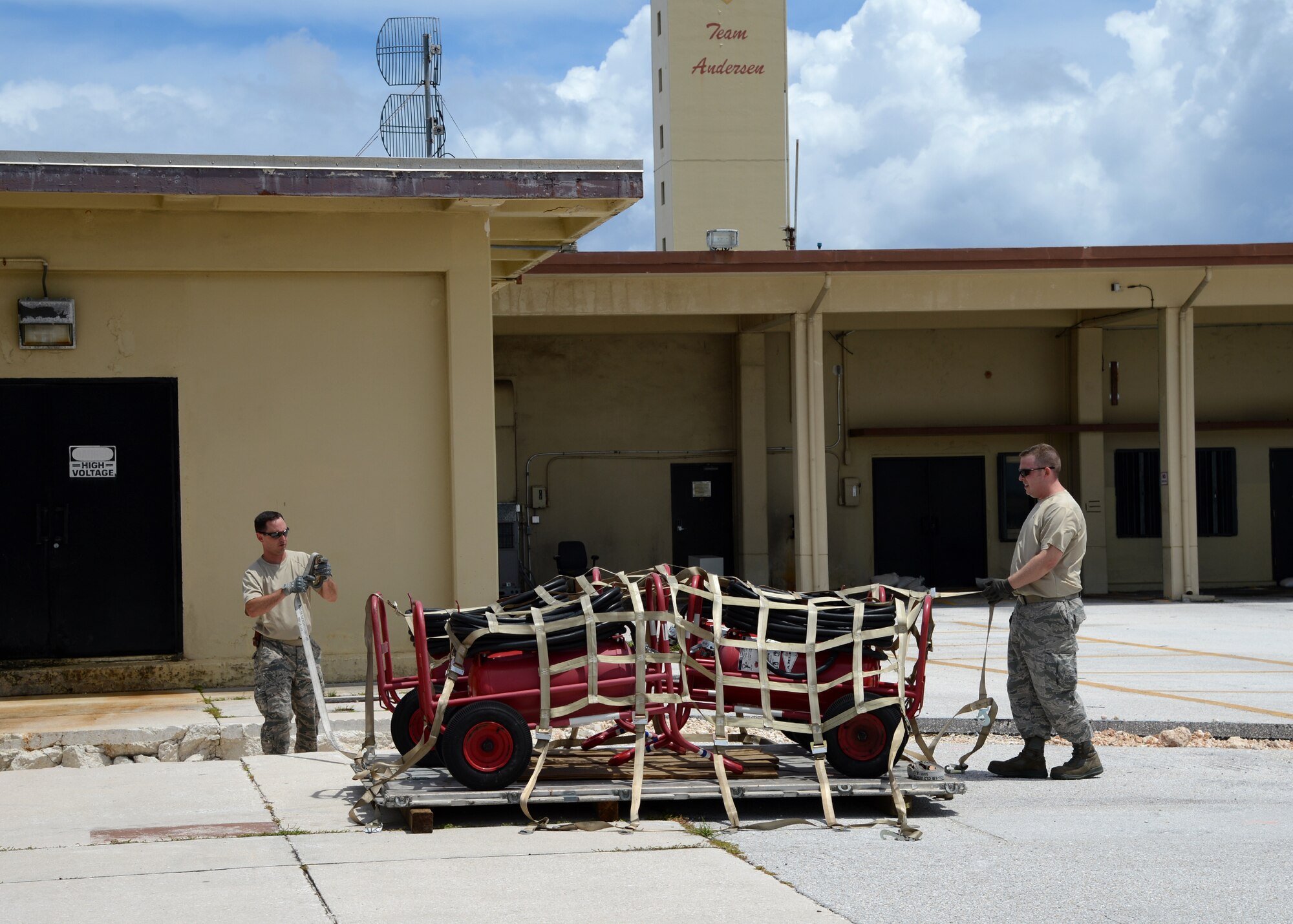 U.S. Air Force Master Sgt. Daniel Jirsa (left), 509th Logistics Readiness Squadron NCO in charge of plans and integration, and Tech. Sgt. Tavis Riley, 509th LRS cargo deployment function craftsman both deployed from Whiteman Air Force Base, Missouri, remove a top net from a pallet at Andersen Air Force Base, Guam, Aug. 19, 2015. The top net was used to secure halon fire extinguisher bottles during transportation from Whiteman to Andersen. (U.S. Air Force photo by Senior Airman Joseph A. Pagán Jr./Released)
