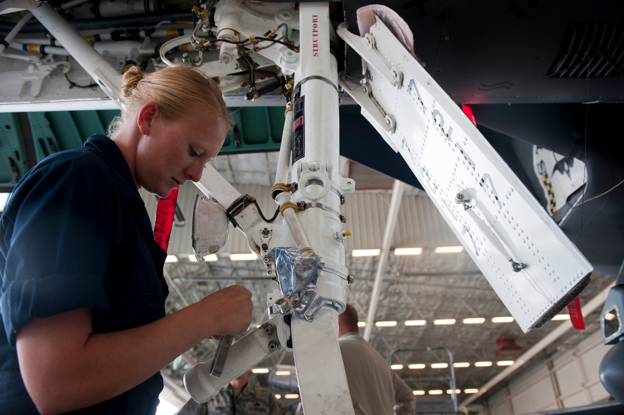 Staff Sgt. Keliah Easley, 757th Aircraft Maintenance Squadron Strike Aircraft Maintenance Unit F-15E Strike Eagle crew chief, installs a nose strut on an F-15E at Nellis Air Force Base, Nev., Aug. 19, 2015. The nose strut helps the front wheel from shimmying. (U.S. Air Force photo by Airman 1st Class Mikaley Towle)