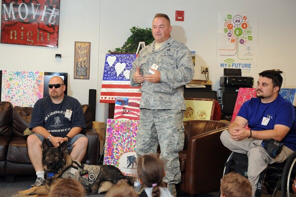 Lt. Col. John Matthews speaks to Schriever School Age Program students, while retired Tech. Sgt. Timothy McDonough and retired Staff Sgt. Chris Wolff look on Friday, Aug. 21, 2015, during a presentation event in the Schriever Child Development Center at Schriever Air Force Base, Colorado.  The three members were invited to the center to speak with the children who presented them with paintings to recognize their service and sacrifice. (U.S. Air Force photo/Dennis Rogers)