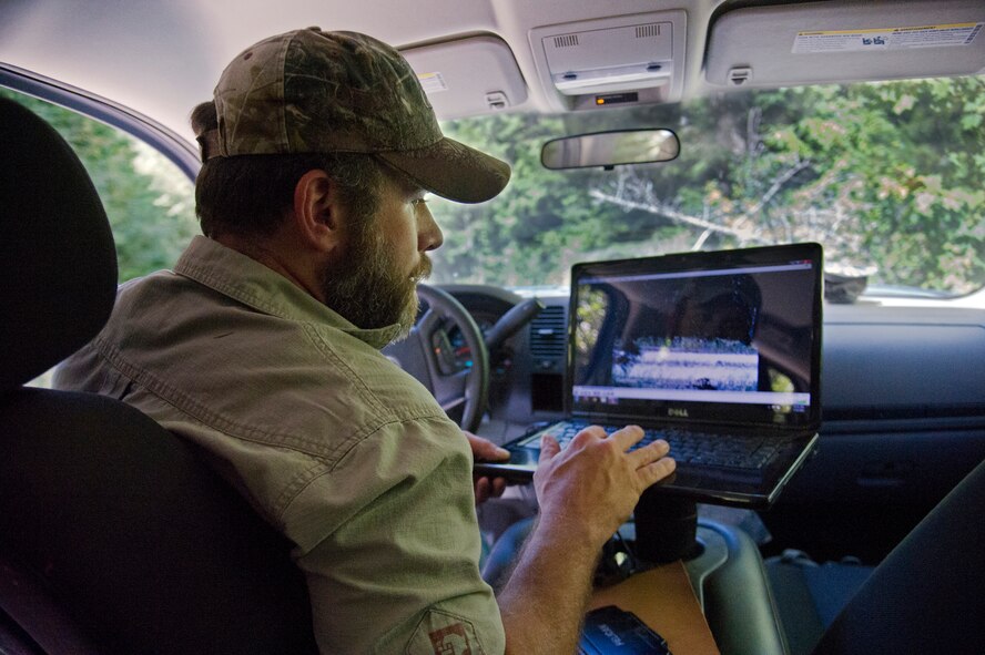 Todd Foster, 336th Training Group training area manager, watches a video recorded with a Bushnell trail camera, July 29, 2015, at Colville National Forest, Wash. Foster has a laptop with video playback capabilities so he can watch video recordings of tracked animals on site. (U.S. Air Force photo/Airman 1st Class Nicolo J. Daniello)