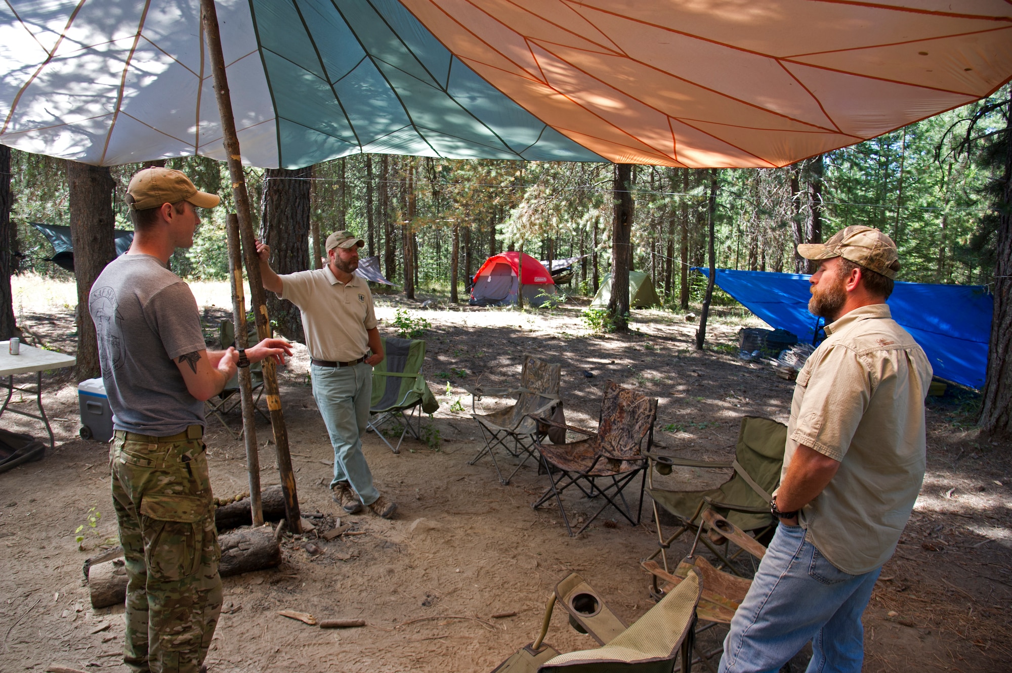 Rick Hall, Air Force liaison to the U.S. Forest Service, and Todd Foster, 336th Training Group training area manager, speak with a Survival, Evasion, Resistance, and Escape specialist, July 29, 2015, at Colville National Forest, Wash. Foster and Hall complete walk throughs at instructor camps to ensure they are within Forest Service standards. (U.S. Air Force photo/Airman 1st Class Nicolo J. Daniello)