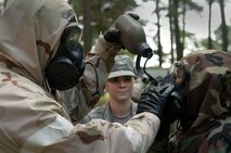 Tech. Sgt. Jessica Clayton (center), 4th Civil Engineer Squadron emergency management NCO in charge, observes Col. Mark Slocum (left), 4th Fighter Wing commander, delivering water through a gas mask to Master Sgt. Shannon Stoner (right), 4th Medical Operations Squadron medical services flight chief, Aug. 25, 2015, at Seymour Johnson Air Force Base, North Carolina. The Ability to Survive and Operate (ATSO) exercise gave Airmen an opportunity to practice putting on their mission-oriented protective posture gear and perform tasks. (U.S. Air Force photo/Airman Shawna L. Keyes) 