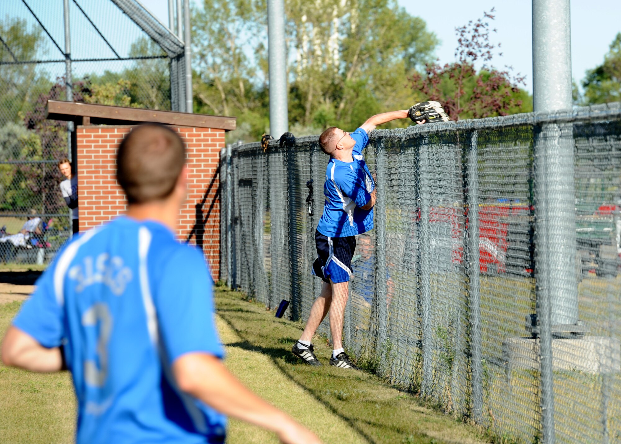 Staff Sgt. Ryan Kuhn, 319th Air Base Wing Honor Guard NCO-in-charge, leans over the fence to make a catch in foul territory during the Intramural Softball Championship game August 24, 2015, on Grand Forks Air Force Base, North Dakota. The 319th Communications Squadron lost to the 69th Reconnaissance Group by a score of four to one. (U.S. Air Force photo by Airman 1st Class Ryan Sparks/Released)