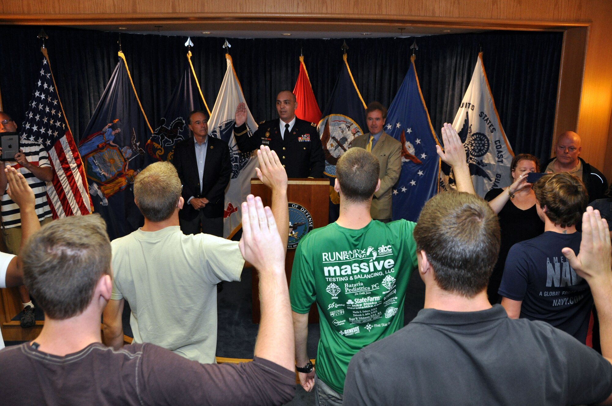 Capt. Marcel Bolboaca-Negru, Operations Officer for the Buffalo Military Entrance Processing Station, is flanked by Congressmen Chris Collins (NY-27) (left) and Congressman Brian Higgins (NY-26) as he administers the Oath of Enlistment to several individuals at the Niagara Falls Air Reserve Station, N.Y. August 25, 2015.  These military service trainees will now journey to their respective basic training sites.  (U.S. Air Force photo by Master Sgt. Kevin Nichols)