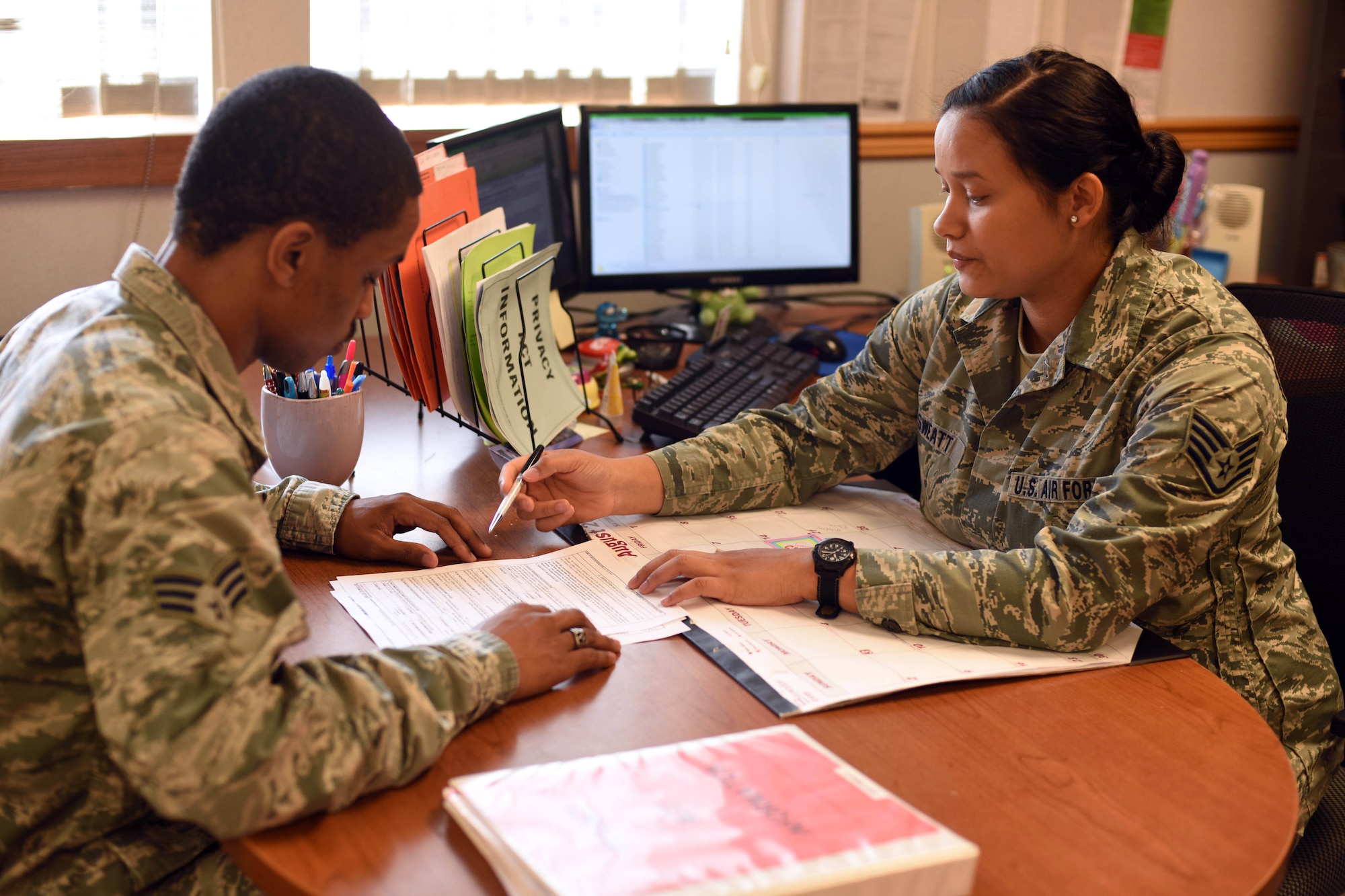 Senior Airman Napoleon Lark, 341st Force Support Squadron career development journeyman, left, evaluates re-enlistment papers with Staff Sgt. Catherine Sweatt, 341st FSS relocations specialist, at Malmstrom Air Force Base, Mont., Aug. 24. Active-duty members must apply and fill out all the required documents before taking the Oath of Enlistment. (U.S. Air Force photo Airman 1st Class Collin Schmidt)