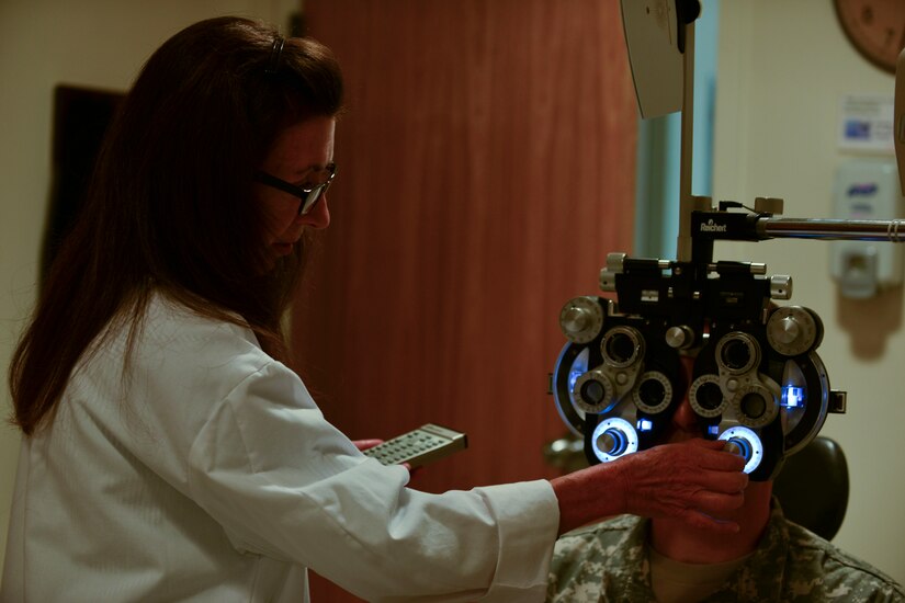 Dr. Robin Collard, McDonald Army Health Center Eye Clinic optometrist, adjusts a phoropter during an eye exam at Fort Eustis, Va., Aug. 21, 2015. The device measures refractive error, which is used to determine eyeglass prescriptions. (U.S. Air Force photo by Staff Sgt. Natasha Stannard/Released)