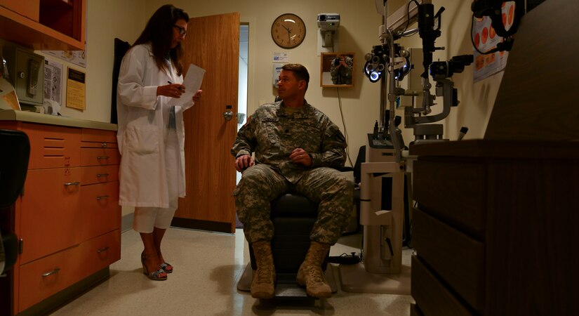 Dr. Robin Collard, McDonald Army Health Center Eye Clinic optometrist, consults U.S. Army Col. Glenn Hodges, U.S. Army Training and Doctrine Command Army Capabilities Integration Center human performance and learning analyst, at Fort Eustis, Va.  Aug. 21, 2015. The eye clinic provides both optometry and ophthalmology services to U.S. Service members, their families and retirees. (U.S. Air Force photo by Staff Sgt. Natasha Stannard/Released)