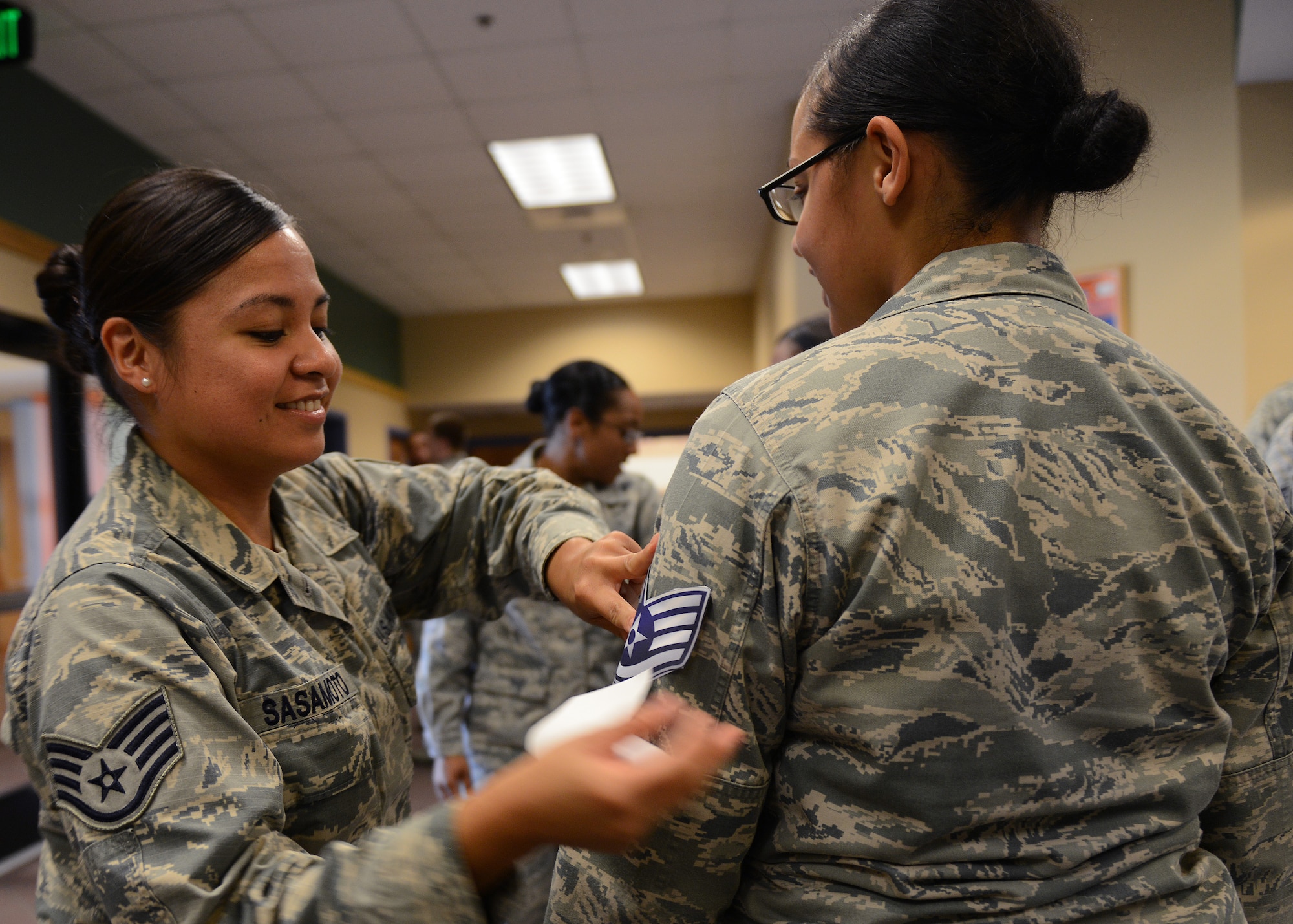 U.S. Air Force Staff Sgt. Maxima Sasamoto, 439th Supply Chain Operations Squadron bombers mission impaired compatibility awaiting parts supervisor, applies a staff sergeant sticker on a senior airman during the Staff Sergeant Release Party at Langley Air Force Base, Va., Aug. 20, 2015. Air Force officials selected 13,269 of 39,260 eligible Senior Airmen for promotion to staff sergeant. (U.S. Air Force photo by Staff Sgt. John D. Strong II/ Released) 