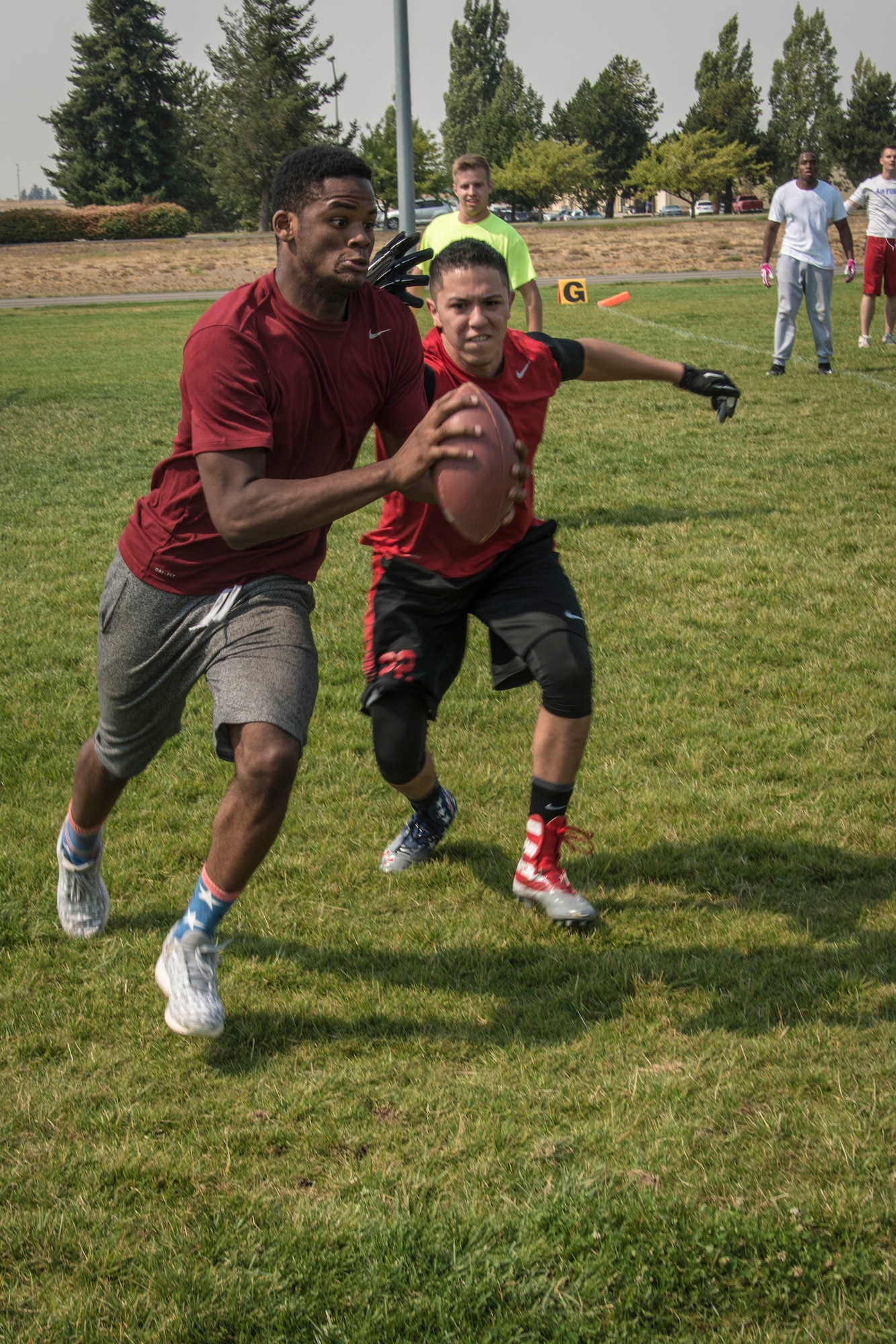 Airman 1st Class Daniel Coleman, 92nd Force Support Squadron services apprentice, scores a touchdown as Senior Airman Joshua Ortega, 92nd Operations Support Squadron boom operator, chases him down while playing defense during Ultimate Football as part of Summer Sports Day Aug. 20, 2015, at Fairchild Air Force Base, Wash. Much like Ultimate Frisbee, Ultimate Football matches two teams against each other with points scored when one catches the football in the end zone. Players are allowed three to five steps after catching the football and then have five seconds to complete a pass to another team member. If the pass is incomplete, the ball turns over to the other team. (U.S. Air Force photo/Staff Sgt. Benjamin W. Stratton)