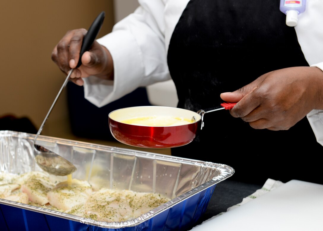 Sonnica Garrett-Jones, “Ingenious Bakery & Catering” chef, pours melted butter on prepared cod during a cooking class at the Community Commons at Langley Air Force Base, Va., Aug 18, 2015. Garrett-Jones taught participants quick and easy recipes, safe food handling procedures and cooking techniques. (U.S. Air Force photo by Airmen 1st Class Derek Seifert/ Released)
