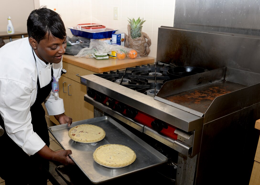 Sonnica Garrett-Jones, “Ingenious Bakery & Catering” chef, places Brie and Bacon Quiche in the oven during a cooking class at the Community Commons at Langley Air Force Base, Va., Aug 18, 2015. The commons employs civilian professionals to teach classes ensuring Service members learn the skills from industry experts. (U.S. Air Force photo by Airmen 1st Class Derek Seifert/ Released)