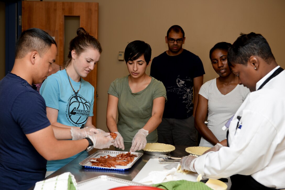 U.S. Air Force Airmen break bacon into pieces during a cooking class at the Community Commons at Langley Air Force Base Aug, Va., 18, 2015. The Community Commons offer cooking classes, musical instrument lessons, jazz dancing, yoga and studio engineering in an effort to provide personnel with life skills. (U.S. Air Force photo by Airmen 1st Class Derek Seifert/ Released)