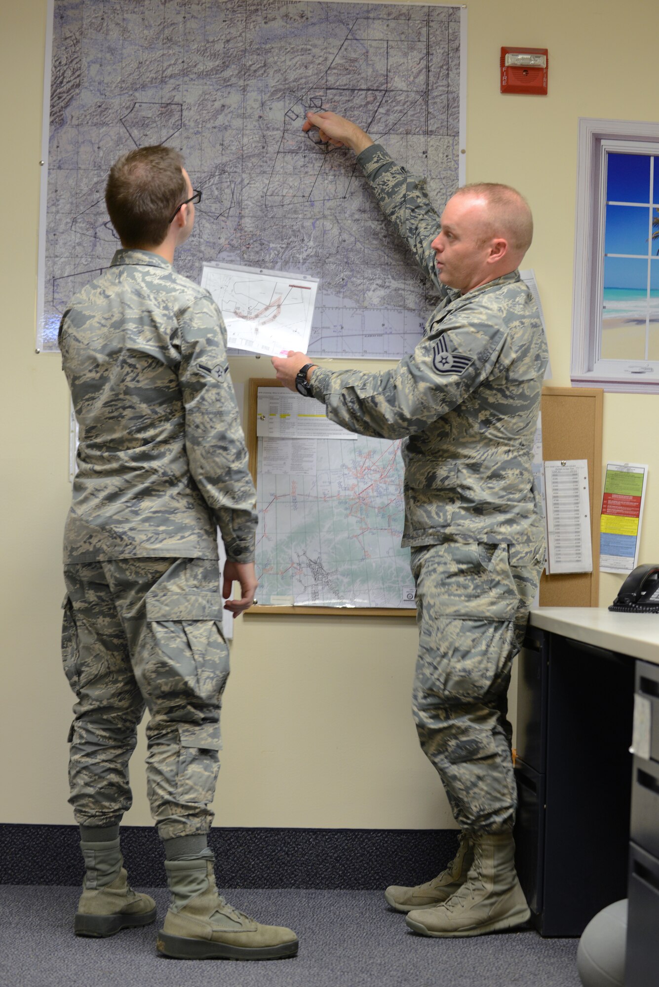 U.S. Air Force Staff Sgt. Matthew Ison, the 354th Operations Support Squadron noncommissioned officer in-charge of current operations, de-conflicts airspace routes of aircraft from various units with Airman Anthony Hurley, the 354th OSS host aviation resource manager Aug. 19, 2015, at Eielson Air Force Base, Alaska. From planning, coordination, scheduling and flying, Ison described his job as a puzzle that needs to be put together every day. (U.S. Air Force photo by Senior Airman Ashley Nicole Taylor/Released)