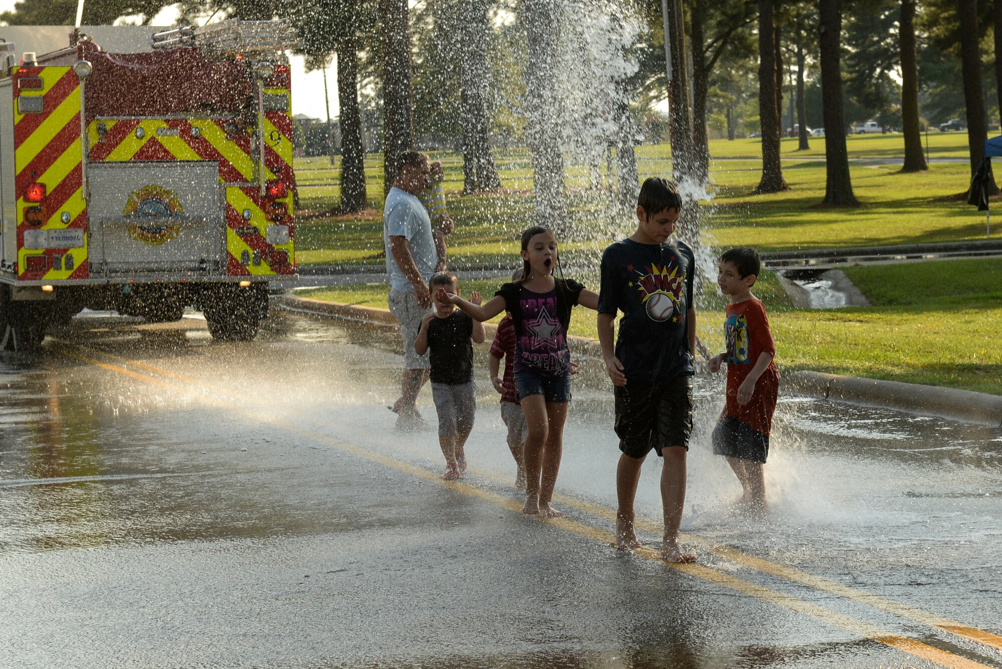 Members of Team Seymour run through water sprayed from a fire truck during the Independence Day Celebration and Back to School Bash, Aug. 21, 2015, at Seymour Johnson Air Force Base, North Carolina. The 4th Civil Engineer Squadron fire department helped ease the hot temperatures and provided entertainment during the bash. (U.S. Air Force photo/Airman 1st Class Ashley Williamson) 