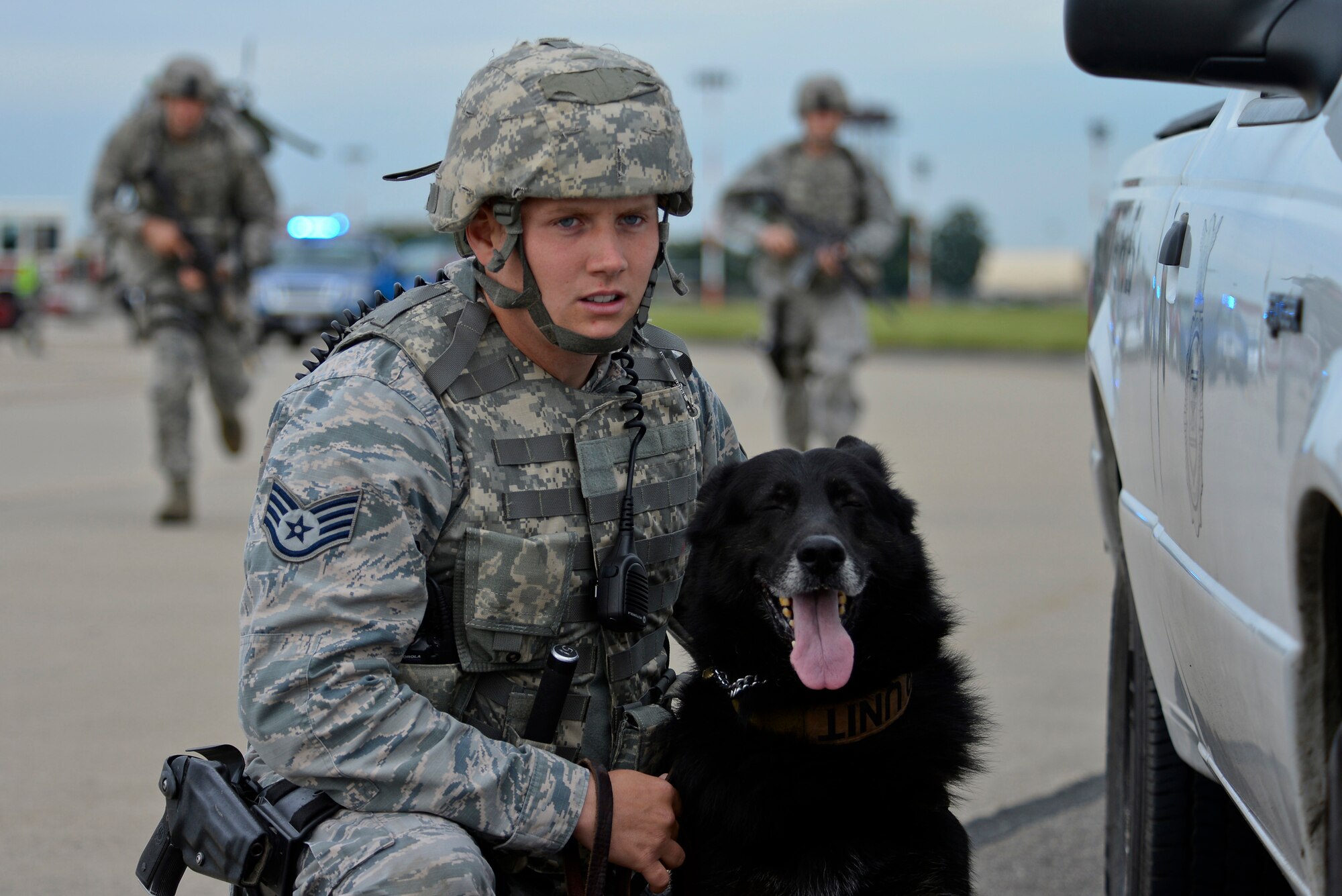 U.S. Air Force Staff Sgt. Roy Carter, 100th Security Forces Squadron military working dog handler, and Luc, 100th SFS military working dog, hold their position as fellow defenders respond during an exercise Aug. 24, 2015, on RAF Mildenhall, England. The exercise was conducted to test first responders and base personnel on their response to and recovery of unauthorized use of U.S. Air Force asset. (U.S. Air Force photo by Staff Sgt. Micaiah Anthony/Released)