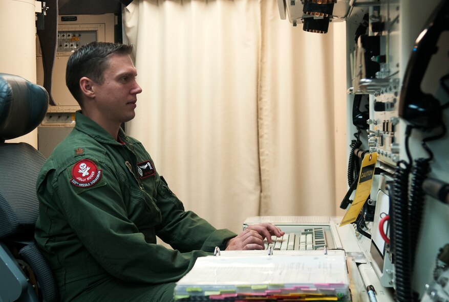Maj. Tom Perry, 320th Missile Squadron missile combat crew member, checks his computer while on alert at the launch control center Aug. 21, 2015. Missileers use computers to check the status of the ICBMs under their command and ensure there are no issues with any of them. (U.S. Air Force by Airman 1st Class Brandon Valle)