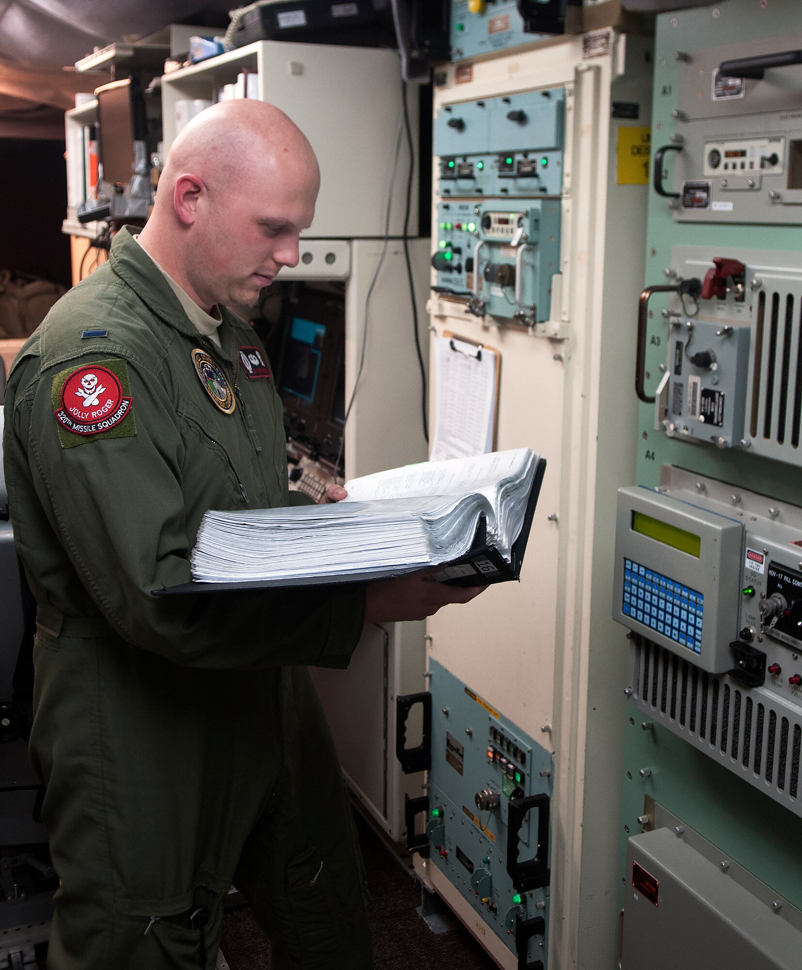 1st Lt. Jonathon Powell, 320th Missile Squadron missile combat crew member, reads from a technical order while checking equipment inside a launch control center Aug. 21, 2015. Technical orders help missileers perform task correctly and safely to prevent any accidents with equipment. (U.S. Air Force by Airman 1st Class Brandon Valle)